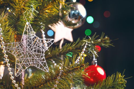 Beautiful Christmas decor concept, bauble hanging on the Christmas tree with sparkling light spot, blurry dark black background, macro detail, close up.