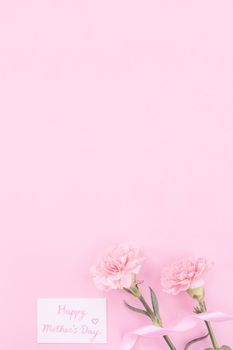 Beautiful, fresh elegant carnation flower bouquet with white greeting thanks gift card isolated on bright pink color background, top view, flat lay concept.