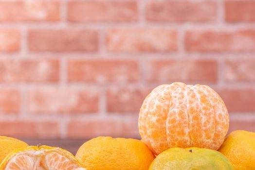 Peeled tangerines in a bamboo sieve basket on dark wooden table with red brick wall background, Chinese lunar new year fruit design concept, close up.