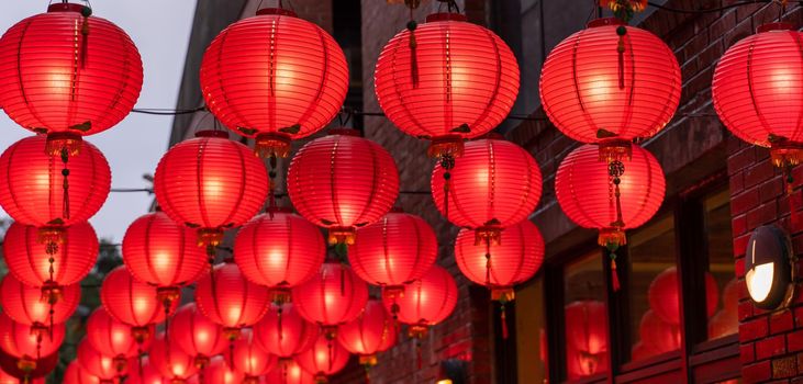 Beautiful round red lantern hanging on old traditional street, concept of Chinese lunar new year festival, close up. The undering word means blessing.