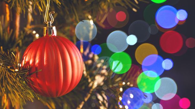 Beautiful Christmas decor concept, bauble hanging on the Christmas tree with sparkling light spot, blurry dark black background, macro detail, close up.