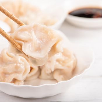 Fresh, delicious boiled pork, shrimp gyoza dumplings on white background with soy sauce and chopsticks, close up, lifestyle. Homemade design concept.