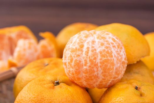 Fresh, beautiful orange color tangerine on bamboo sieve over dark wooden table. Seasonal, traditional fruit of Chinese lunar new year, close up.
