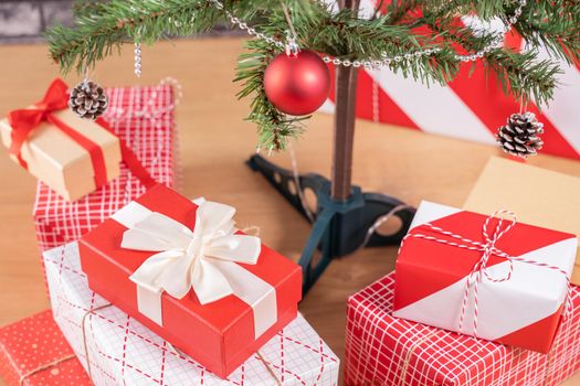 Decorated Christmas tree with wrapped beautiful red and white gifts at home with black brick wall, festive design concept, close up.