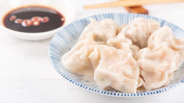 Fresh, delicious boiled pork gyoza dumplings, jiaozi on white background with soy sauce and chopsticks, close up, lifestyle. Homemade design concept.