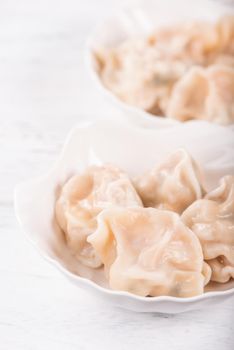 Fresh, delicious boiled pork gyoza dumplings, jiaozi on white background with soy sauce and chopsticks, close up, lifestyle. Homemade design concept.