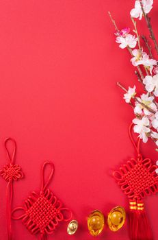 Design concept of Chinese lunar new year - Beautiful Chinese knot with plum blossom isolated on red background, flat lay, top view, overhead layout.