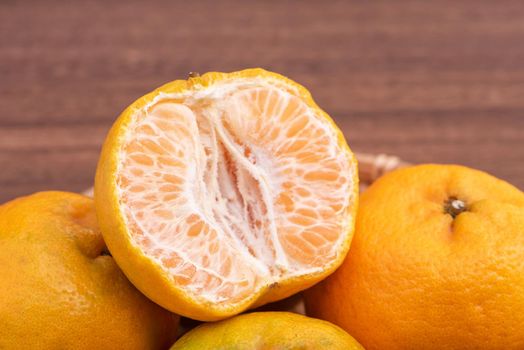 Fresh, beautiful orange color tangerine on bamboo sieve over dark wooden table. Seasonal, traditional fruit of Chinese lunar new year, close up.