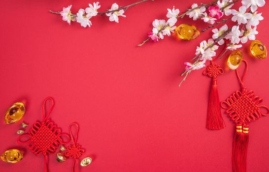 Design concept of Chinese lunar new year - Beautiful Chinese knot with plum blossom isolated on red background, flat lay, top view, overhead layout.
