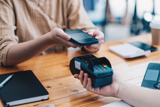 A woan using her mobile to made a payment wireless with EDC machine or credit card terminal. Mobile payment concept with virtual credit card.