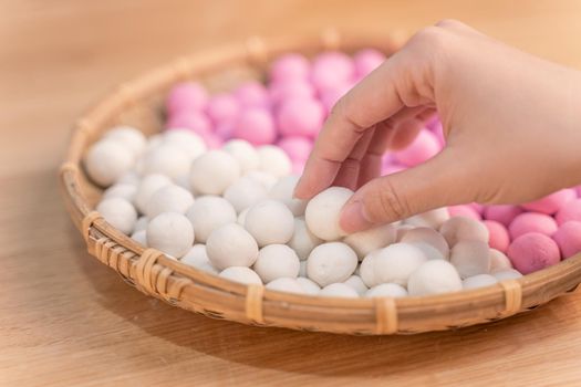 An Asia woman is making Tang yuan, yuan xiao, Chinese traditional food rice dumplings in red and white for lunar new year, winter festival, close up.