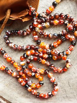 Sunny beads of amber fireplace faceted agate with leather jewelry pouch bag on rustic background