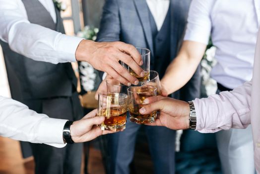 Cropped view of Group of friends guys with glasses of whiskey before wedding day