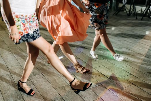 New year, celebration, disco concept - women in evening dresses dancing in club, part of body female legs in high heels on party floor