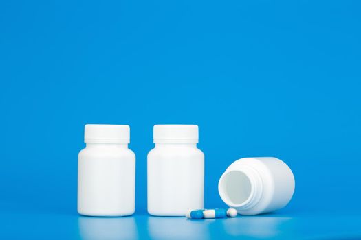 Minimal still life white medication bottles with pills against blue background with copy space. Concept of healthcare and medical treatment