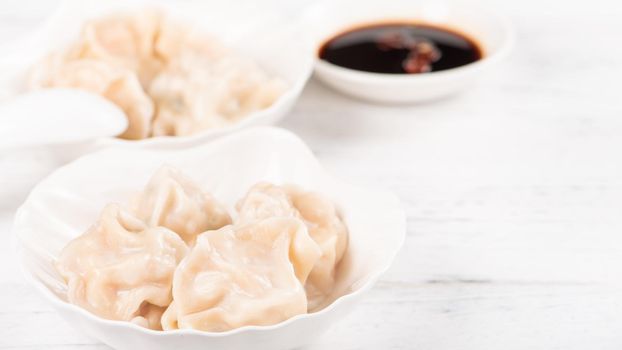 Fresh, delicious boiled pork, shrimp gyoza dumplings on white background with soy sauce and chopsticks, close up, lifestyle. Homemade design concept.