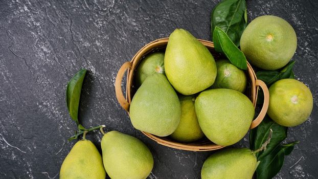 Fresh peeled pomelo, pummelo, grapefruit, shaddock on dark background in bamboo basket. Autumn seasonal fruit, top view, flat lay, tabletop shot.