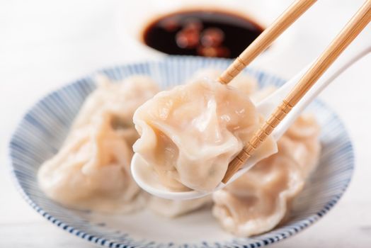 Fresh, delicious boiled pork, shrimp gyoza dumplings on white background with soy sauce and chopsticks, close up, lifestyle. Homemade design concept.