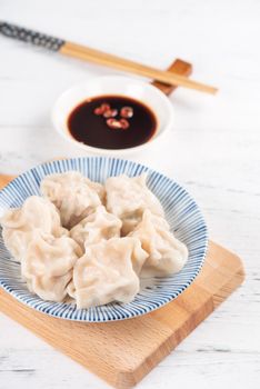 Fresh, delicious boiled pork, shrimp gyoza dumplings on white background with soy sauce and chopsticks, close up, lifestyle. Homemade design concept.