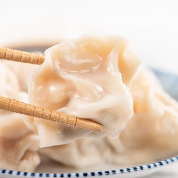 Fresh, delicious boiled pork, shrimp gyoza dumplings on white background with soy sauce and chopsticks, close up, lifestyle. Homemade design concept.