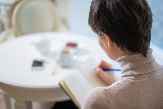 Pondering attractive young woman with pen in hand thinking on plans