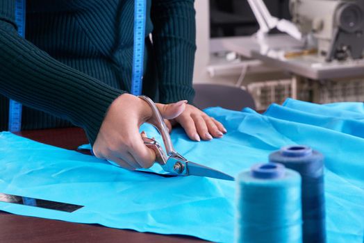 Dressmaker cutting fabric in atelier shop