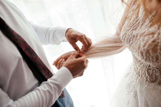 Groom is helping a bride with her dress, a romantic concept