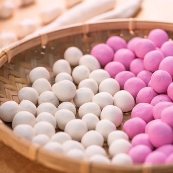 An Asia woman is making Tang yuan, yuan xiao, Chinese traditional food rice dumplings in red and white for lunar new year, winter festival, close up.