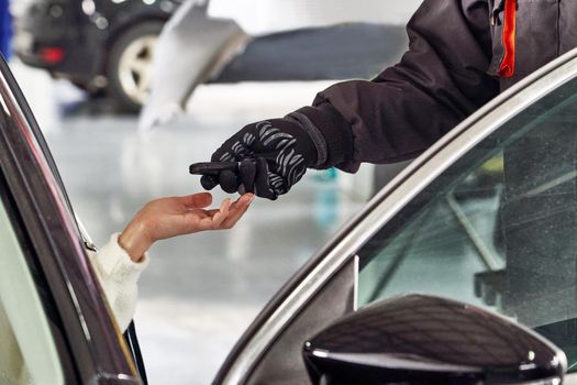Professional Car Mechanic Giving Client Keys from her Repaired Car In Auto Repair Service