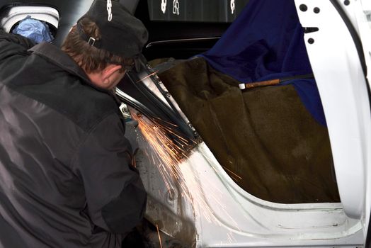 Cutting metal part with sparks in car service station