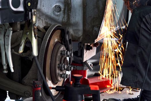 Cutting metal part with sparks in car service station