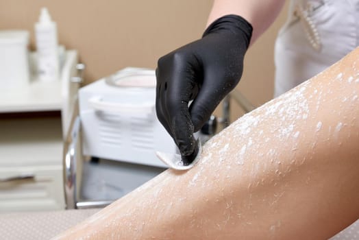 Beautician getting ready to wax female legs in spa center