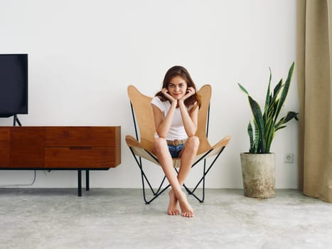 Woman sitting in leather armchair smile with teeth Lifestyle, relaxing at home stylish modern interior with white walls, copy space. High quality photo