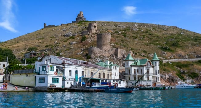 BALAKLAVA, UKRAINE - JUNE 27, 2012: View from the sea to the ruins of the fortress and modern buildings on the shore in Balaklava Bay, Black Sea
