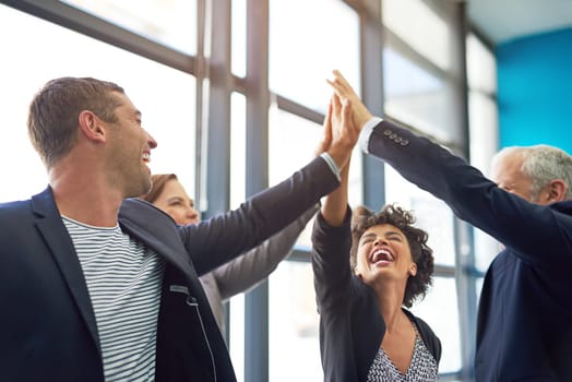 Business people, group high five and happy in office with teamwork, smile and support for company goals. Men, women and hands in air for team building, achievement and celebration at insurance agency.