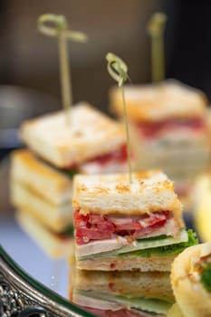 mini canape sandwiches with sausage and white bread close-up.