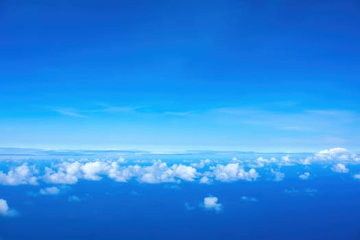 Line of fluffy white clouds just below horizon over blue ocean