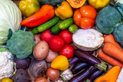 Various vegetables are laid out on a wooden table. Large assortment of vegetables food. pumpkin cabbage broccoli pepper tomatoes carrots and others.