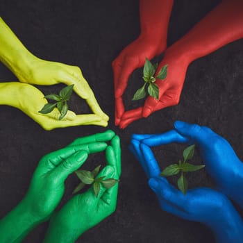 Nature will be proud. unrecognizable people holding budding plants in their multi colored hands