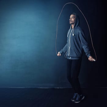 Feeling skippy. Studio shot of a young man skipping against a dark background