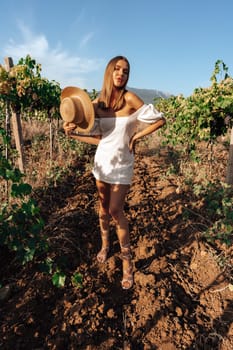 Beautiful young blonde woman walking outdoors in vineyard in summer time