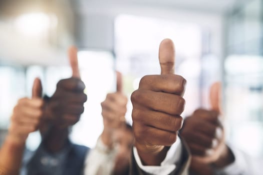 We appreciate the work youre doing. Closeup shot of a group of businesspeople showing thumbs up in an office