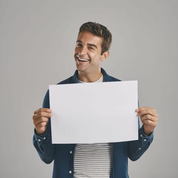 I have a very special message just for you. Studio portrait of a young man holding a blank placard against a grey background