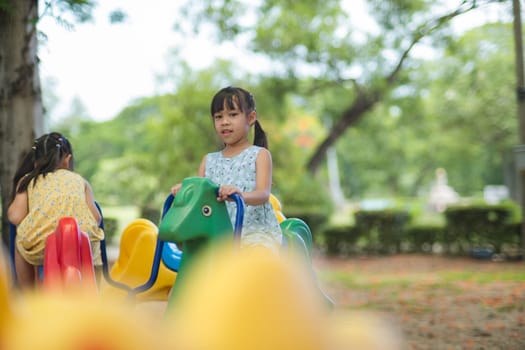 Happy girl having fun on a carousel. Children playing at outdoor playground in the park on summer vacation. Healthy activity.