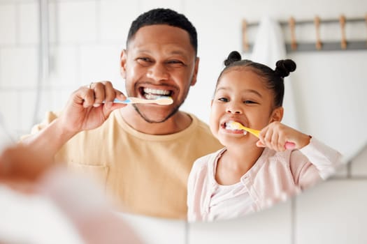Child, dad and brushing teeth in a family home bathroom for dental health and wellness in a mirror. Face of african man and girl kid learning to clean mouth with toothbrush and smile for oral hygiene.