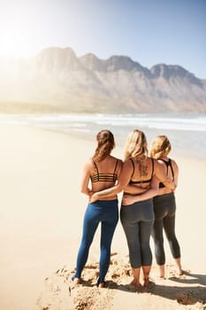 Live a peaceful life. Rearview shot of three young yogis standing on the beach