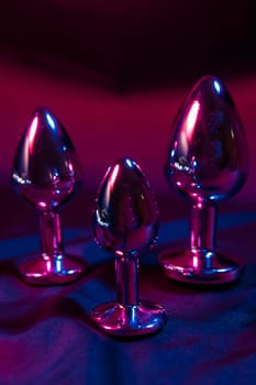 Lots of metal anal plugs in neon pink purple light