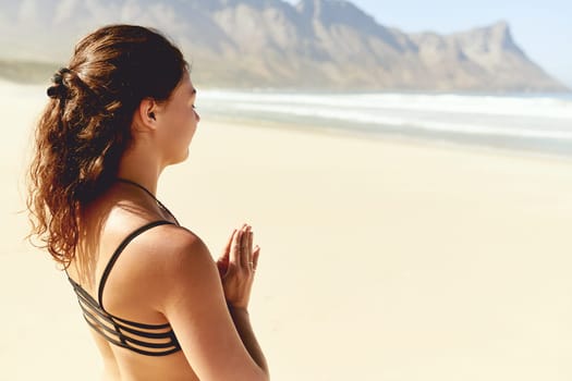 Yoga heals you inside out. a beautiful young woman practising yoga on the beach