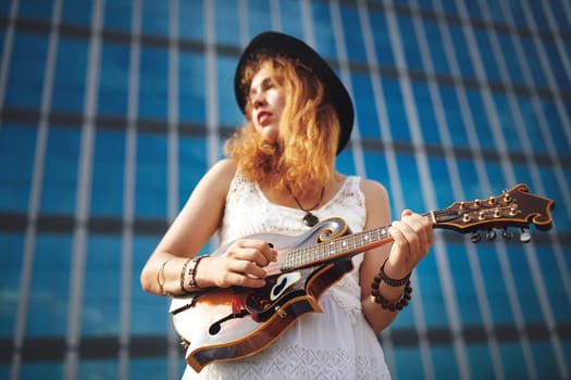 Music helps me to express myself. a beautiful young woman out in the city with her guitar