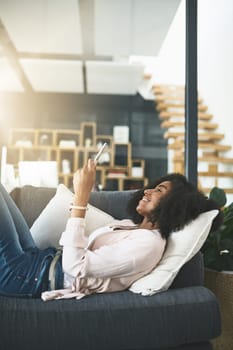 Never alone with technology keeping her connected. an attractive young woman relaxing at home